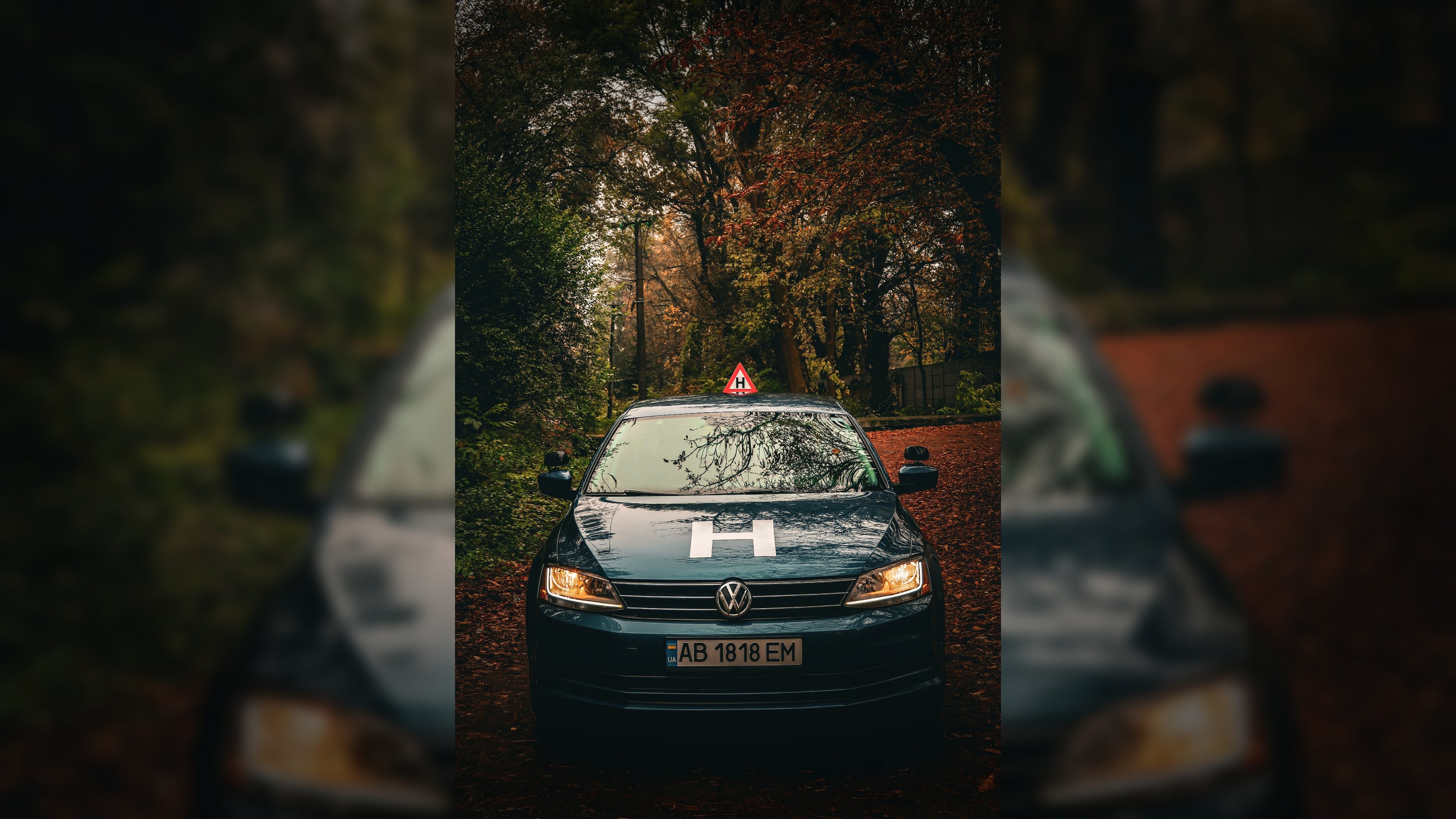 Навчальний автомобіль автошколи Меркурій на дорозі серед осіннього лісу